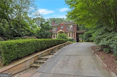 View of front of property featuring brick siding, a chimney, and driveway