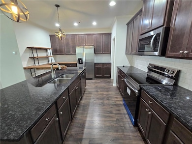 Kitchen featuring appliances with stainless steel finishes, a sink, ornamental molding, dark wood-type flooring, and dark brown cabinets