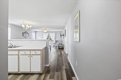 Kitchen featuring light countertops, dark wood-type flooring, a sink, a peninsula, and baseboards