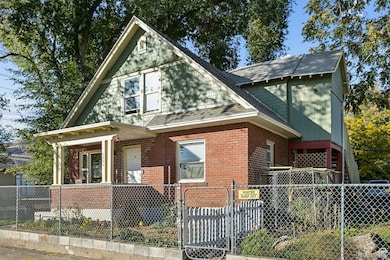 View of front of house featuring a gate, a fenced front yard, roof with shingles, and brick siding