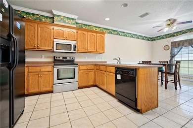 Kitchen with black appliances, a textured ceiling, a peninsula, light tile patterned floors, and crown molding