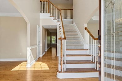 Stairs with crown molding, baseboards, arched walk