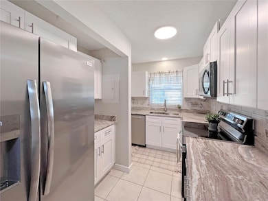 Beautifully updated Kitchen featuring white shaker, wood cabinets, granite countertop, stainless steel appliances and custom tiled backsplash.