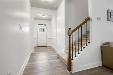 Entryway with arched walkways, wood finished floors, and stairway