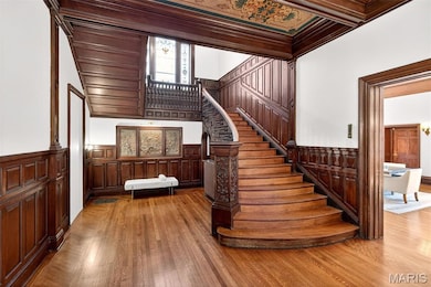 Stairs with wainscoting, a decorative wall, wood finished floors, and ornamental molding