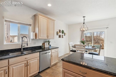 Kitchen with light brown cabinetry, a chandelier, 