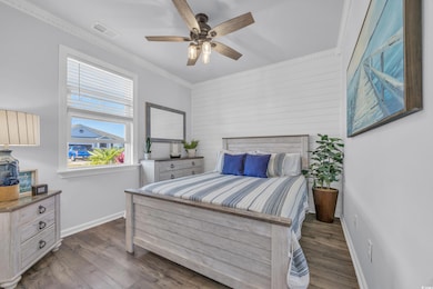 Bedroom featuring wood finished floors, baseboards, ornamental molding, ceiling fan, and wooden walls
