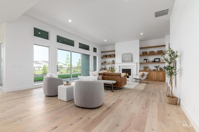 Living area with a warm lit fireplace, light wood-style floors, and recessed lighting