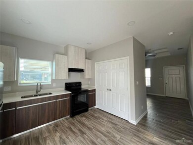 Kitchen featuring black / electric stove, a sink, light countertops, under cabinet range hood, and modern cabinets