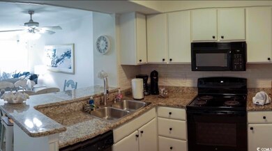 Kitchen with black appliances, a peninsula, a sink, a ceiling fan, and backsplash