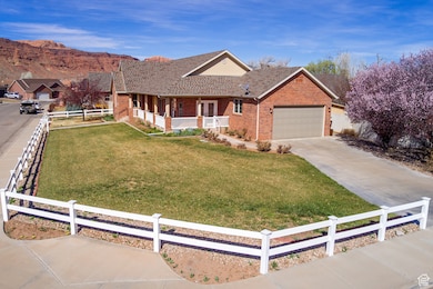 Ranch-style house featuring fence, driveway, a front lawn, covered porch, and brick siding