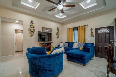 Living area featuring a tray ceiling, ceiling fan, and light tile patterned flooring