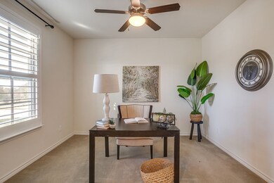 Carpeted office with a ceiling fan and baseboards
