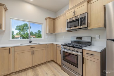Kitchen featuring light brown cabinetry, appliances with stainless steel finishes, and light wood-style flooring