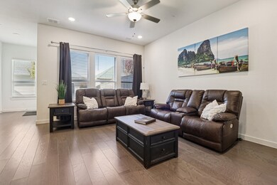 Living area with dark wood-style flooring, a ceiling fan, and recessed lighting