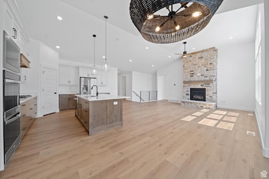 Kitchen with open floor plan, recessed lighting, decorative light fixtures, a kitchen island with sink, and white cabinetry