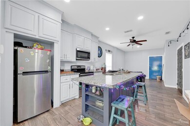 Kitchen featuring appliances with stainless steel finishes, a breakfast bar, white cabinetry, light wood finished floors, and open shelves