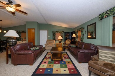 Carpeted living room featuring a ceiling fan, a textured ceiling, and vaulted ceiling