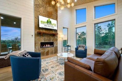 Living area with wood finished floors, a stone fireplace, a towering ceiling, and a chandelier
