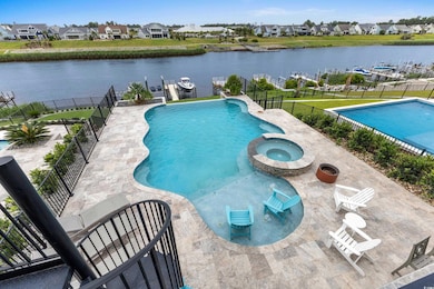 View of pool with a water view, a pool with connected hot tub, a residential view, and a patio area