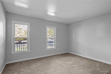 Carpeted spare room featuring baseboards