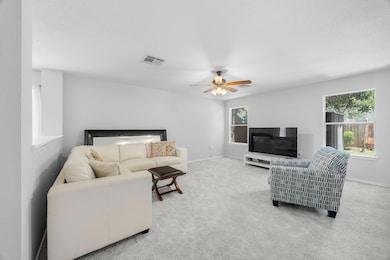 Carpeted living area featuring ceiling fan and ba