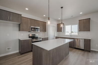Kitchen featuring decorative backsplash, pendant lighting, appliances with stainless steel finishes, light wood-style flooring, and recessed lighting