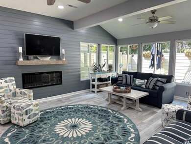 Living area with ceiling fan, wood finished floors, a fireplace, and wooden walls