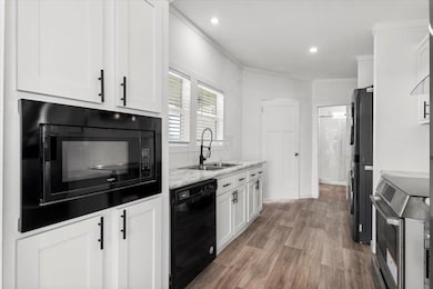 Kitchen featuring black appliances, white cabinet