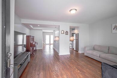 Living area featuring dark wood-style flooring and baseboards