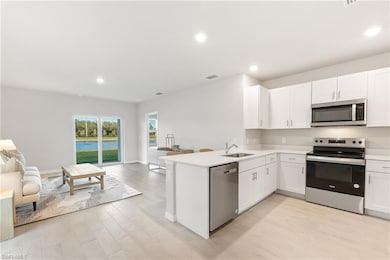 Kitchen featuring appliances with stainless steel finishes, open floor plan, a sink, light countertops, and a peninsula