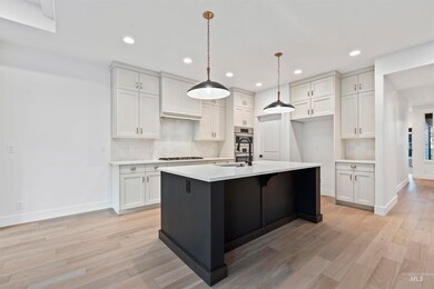 Kitchen featuring backsplash, decorative light fixtures, white cabinetry, light wood-type flooring, and recessed lighting