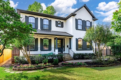 The exterior showcases timeless design with freshly painted stucco accented by striking black shutters. Expansive windows and a spacious front porch with elegant wrought iron railing create a stunning first impression. The roof was replaced in October 2025!