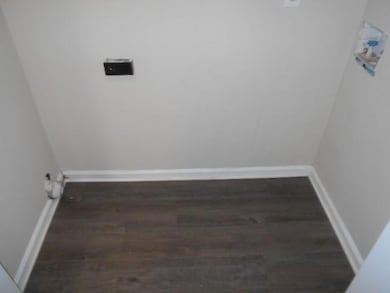 Laundry room with dark wood-type flooring and base