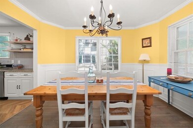 Dining room with a chandelier, wainscoting, ornamental molding, and healthy amount of natural light