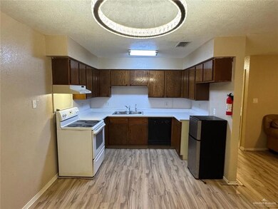 Kitchen featuring white electric stove, freestanding refrigerator, a sink, under cabinet range hood, and dishwasher