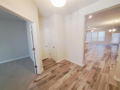 Corridor with wood finish floors and a chandelier