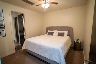 Bedroom with ceiling fan and dark colored carpet
