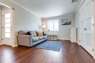 Living room with dark wood finished floors and crown molding