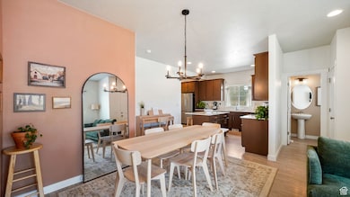 Dining area with a chandelier, light wood-style floors, arched walkways, and recessed lighting