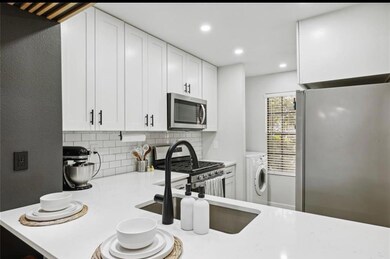 Enjoy cooking in the fully updated kitchen featuring sleek white shaker cabinets, quartz countertops, subway tile backsplash, and modern black hardware. Stainless steel appliances, gas range, and a deep farmhouse-style sink complete this stylish space.