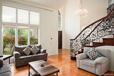 Living room with a high ceiling, light wood-type flooring, a chandelier, and stairway