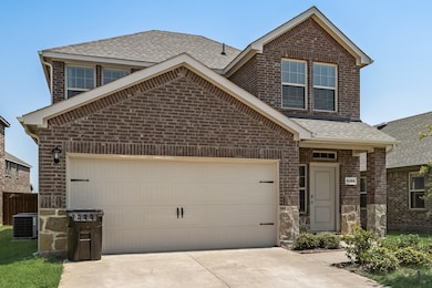 Traditional-style house featuring brick siding, driveway, roof with shingles, and a garage