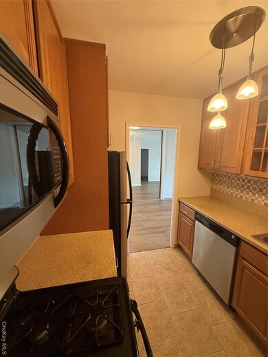 Kitchen featuring backsplash, stainless steel range, dishwashing machine, light tile patterned floors, and light stone counters
