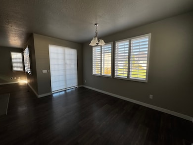 Unfurnished dining area with a textured ceiling and dark wood finished floors
