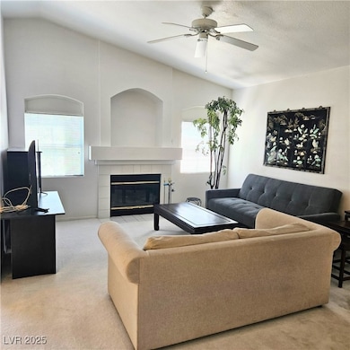 Carpeted living area with a tile fireplace, a ceil