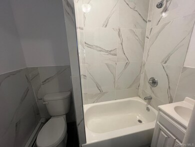 Bathroom featuring tile walls, vanity, bathtub / shower combination, wainscoting, and baseboard heating