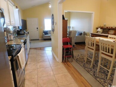 Kitchen featuring a sink, stainless steel appliances, white cabinetry, lofted ceiling, and light tile patterned floors