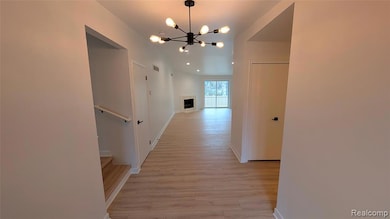 Hallway with a chandelier, light wood finished floors, and recessed lighting