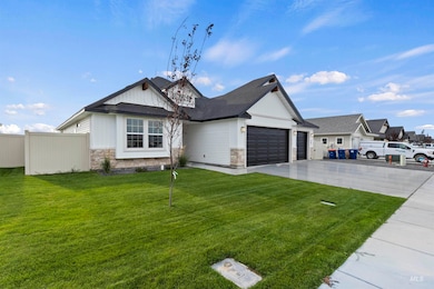 View of front facade with stone siding, driveway, an attached garage, and roof with shingles